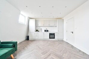 Een moderne keuken met witte kasten, een inbouwoven en een visgraat parketvloer.
