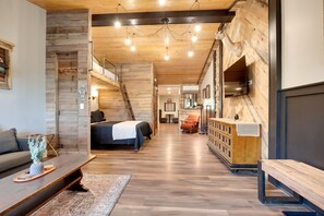 A modern interior with a wooden floor, a bed, a sofa, and a bench. - Suite 1 – The Harris Inn in Harrison Hills (Tomahawk)