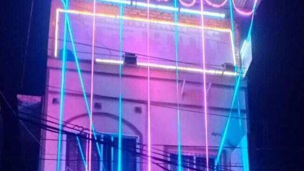 A building with neon lights forming geometric patterns on the facade. - ANNAPURNA GUEST HOUSE (Nagpur)