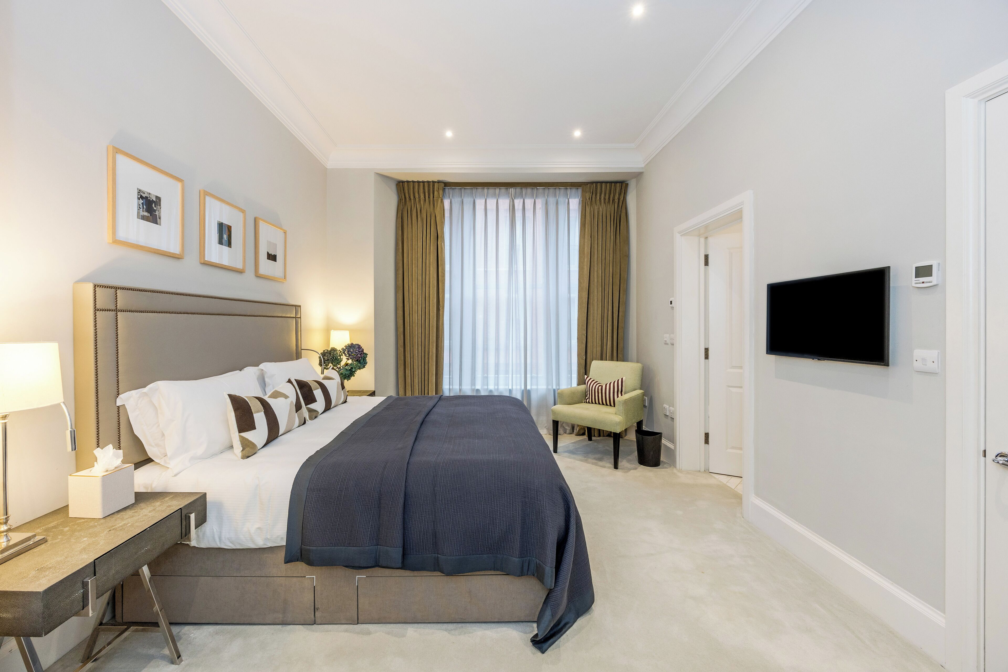 Una habitación de hotel con una cama grande, mesitas de noche, un televisor y una silla.