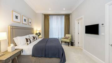 Una habitación de hotel con una cama grande, mesitas de noche, un televisor y una silla.