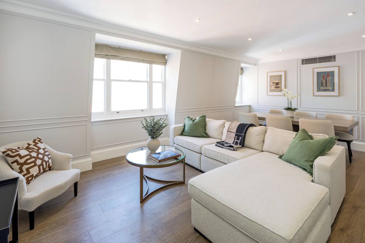 A spacious living room with a beige sofa, a coffee table, and a window with beige curtains.