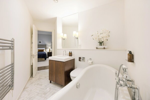 Un baño moderno con bañera, lavamanos, inodoro y espejo.