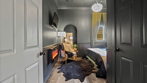 A bedroom with a bed, a chair, a fireplace, and a television on the wall. - Huge outdoor space walk to everything (Ocean Springs)