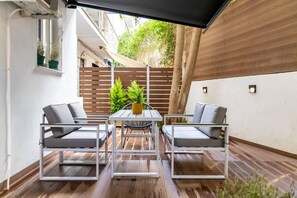 A patio with two white metal-framed chairs, a small table, and a yellow pot.