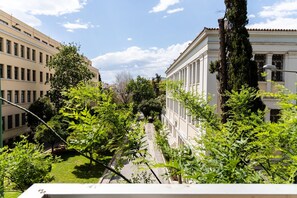 A view of a building with classical architecture, including columns and a symmetrical facade, surrounded by greenery and a clear sky. - Luxury Flat at Archaeological Museum (Athens)