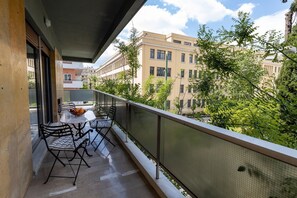 A balcony with a table and chairs, overlooking a cityscape with buildings and trees. - Luxury Flat at Archaeological Museum (Athens)