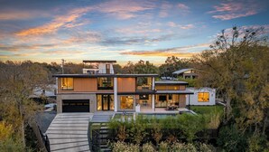 Une maison moderne à deux étages, dotée d’une vaste terrasse, d’un garage et d’un jardin bien entretenu.