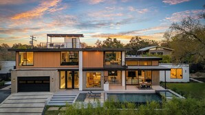 Une maison moderne à plusieurs étages, dotée d’une piscine, de grandes fenêtres et d’un garage.
