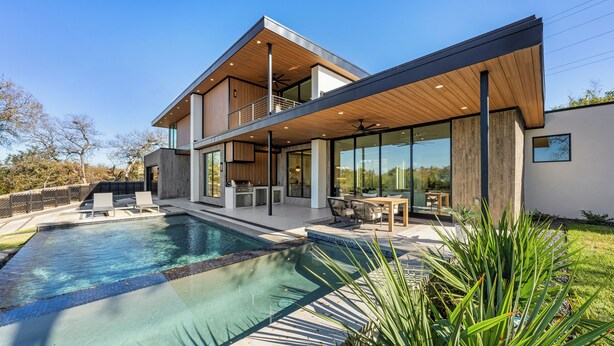 Une maison moderne dotée d’une piscine, de mobilier d’extérieur et d’un patio couvert.