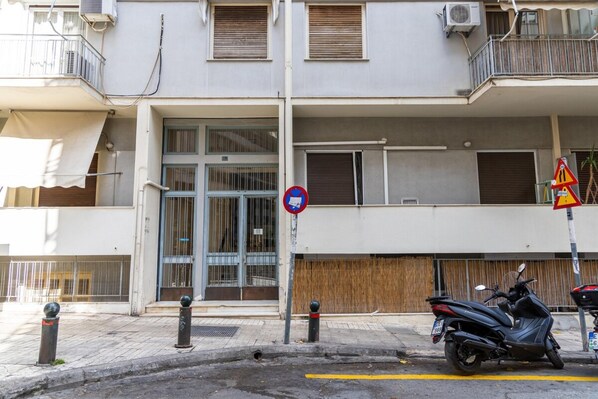 A building with a gated entrance, a no parking sign, and a motorcycle parked on the sidewalk. - Acropolis Museum Amazing Studio (Athens)