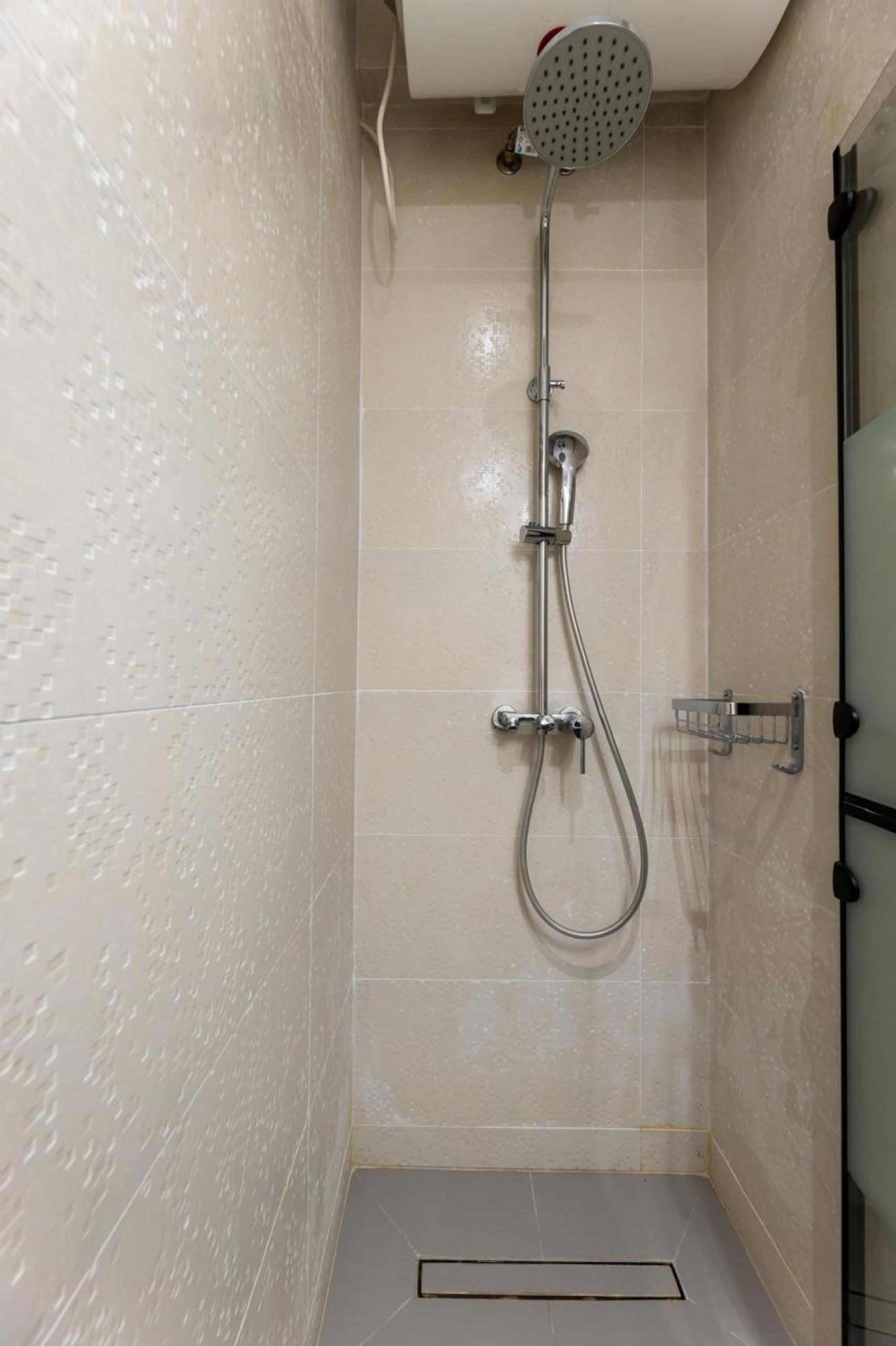 Un espacio de ducha pequeño con azulejos, un cabezal de ducha de mano y un grifo empotrado en la pared.