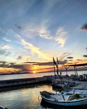 A sunset view from a dock with boats and a pier.