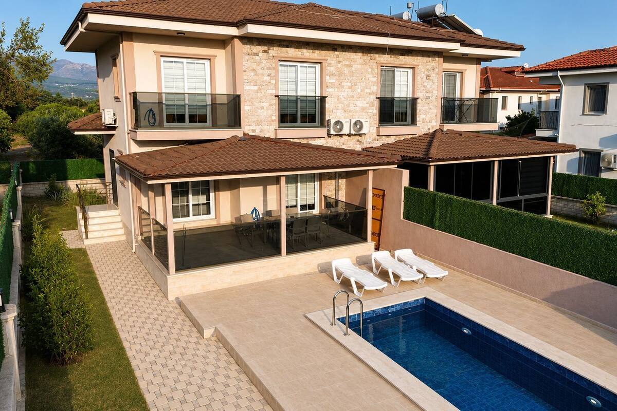 Una casa de dos pisos con piscina, mobiliario exterior y un porche cubierto.