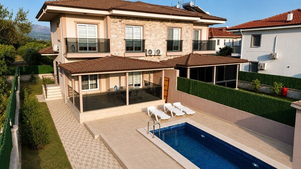 A two-story house with a swimming pool, outdoor seating, and a covered patio. - Likya Karya Villaları (Koycegiz)