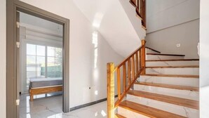 Una escalera con escalones de madera y un vidrio que da a una habitación con cama.