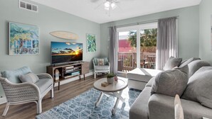 Een woonkamer met een televisie, zitplaatsen en kunstwerken.