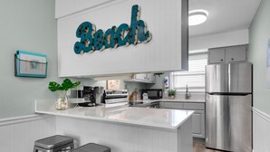 Een moderne keuken met een centraal eiland, roestvrijstalen apparatuur en een bord met de tekst 'Beach' erboven.