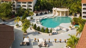 A resort with a large pool, lounge areas, and multiple buildings with balconies. - 2-Bedroom Luxury Villa in Lovely Puerto Plata with AC, WiFi sleeps 8! (Puerto Plata)