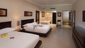 A hotel room with two beds, a bathroom with a bathtub, a TV, and artwork on the walls. - 2-Bedroom Luxury Villa in Lovely Puerto Plata with AC, WiFi sleeps 8! (Puerto Plata)
