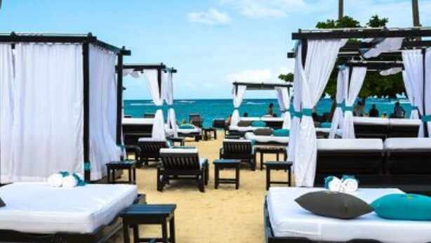 A beachside hotel room with a bed, a small table, and a chair. - 2-Bedroom Luxury Villa in Lovely Puerto Plata with AC, WiFi sleeps 8! (Puerto Plata)