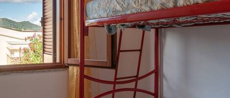 Una cama litera con un colchón estampado, una escalera y una ventana con cortinas.