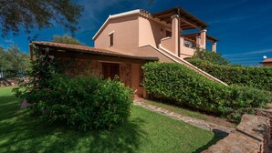 A two-story house with a stone facade, a balcony, and a well-maintained garden.