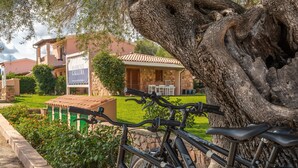 A residential property with a stone facade, a patio with outdoor furniture, and a bicycle parked in front.
