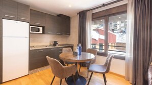 Une cuisine moderne avec des meubles de couleur sombre, un four à micro-ondes et une table de salle à manger ronde, accompagnée de chaises.