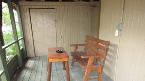 A wooden bench and table on a wooden deck with a green railing, a beige wall, and a door in the background. - SpringHouse at Convict Springs (Mayo)