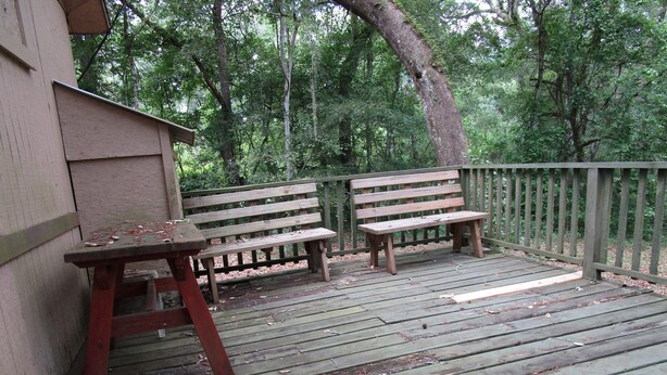A wooden deck with two benches and a table, surrounded by a wooden fence and trees. - SpringHouse at Convict Springs (Mayo)