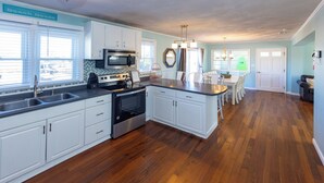 A kitchen with white cabinets, a stainless steel sink, and a wooden floor.