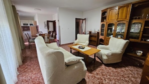 A living room with two armchairs, a coffee table, and a wooden cabinet with glass doors. - Apartment in Nature (Kastelir-Labinci)
