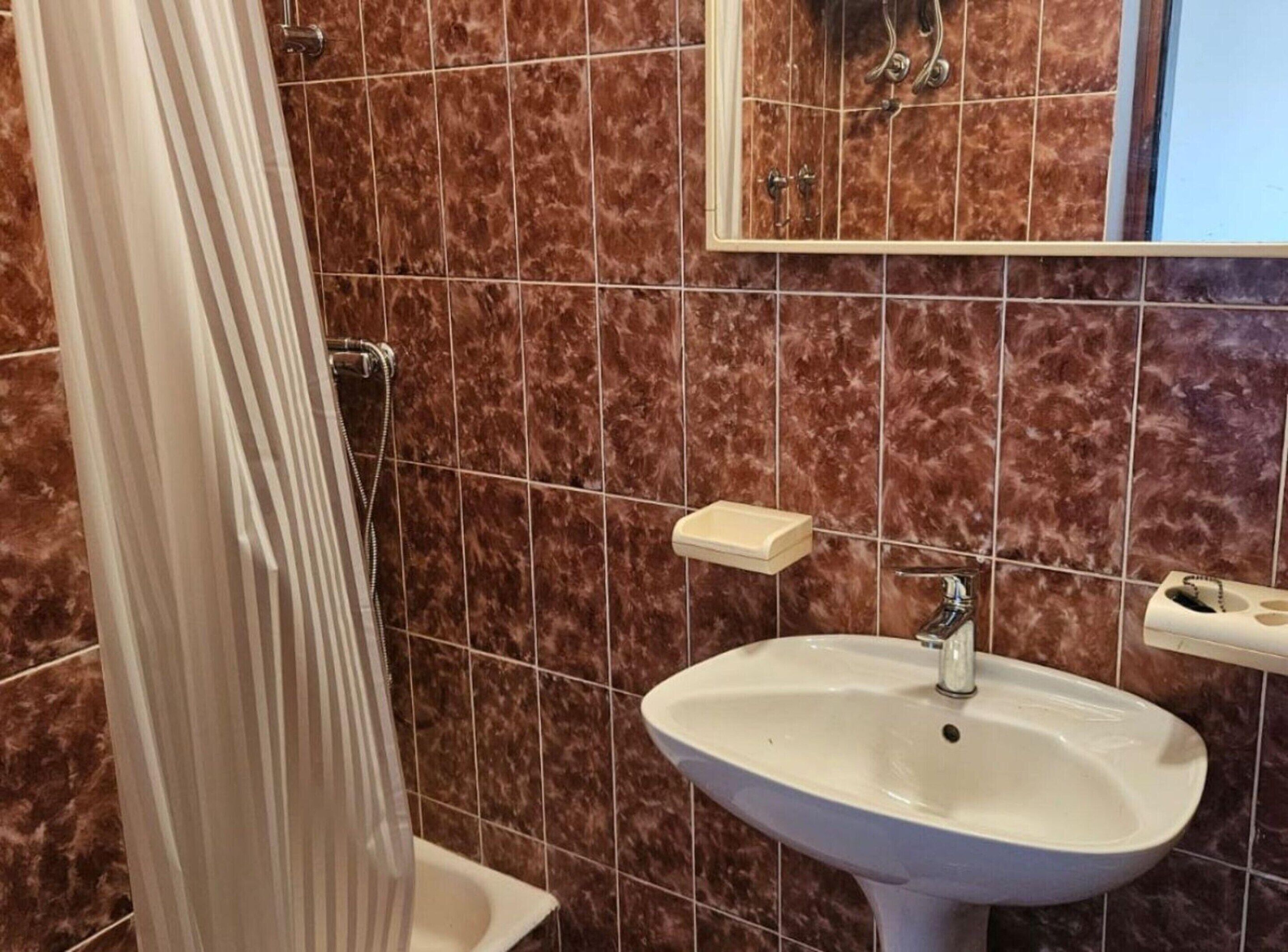 A bathroom with a white sink, a mirror, and a shower curtain.