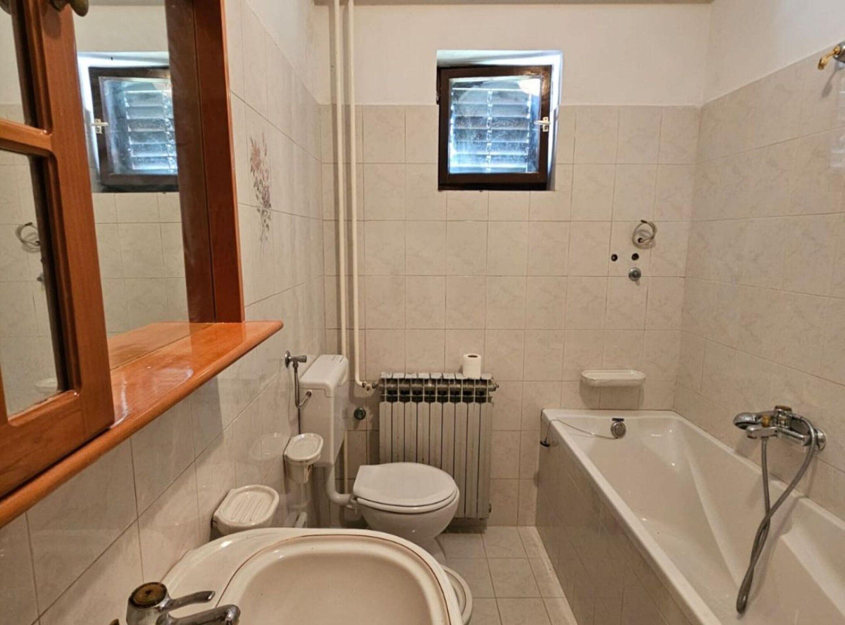 Une salle de bain comprenant des toilettes, un bidet, un lavabo, une baignoire et une fenêtre.