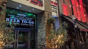 Un bâtiment avec une enseigne indiquant « UP THE CREEK COMEDY CLUB » et une autre indiquant « BEER TO GO », avec un bar et une brasserie sur place.
