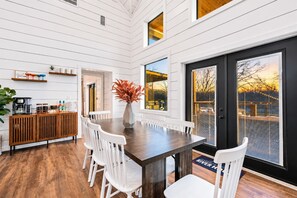 Gather at the six-seat dining table beside large farmhouse-style windows and glass doors—an inviting place for breakfast, takeout, or family dinners.