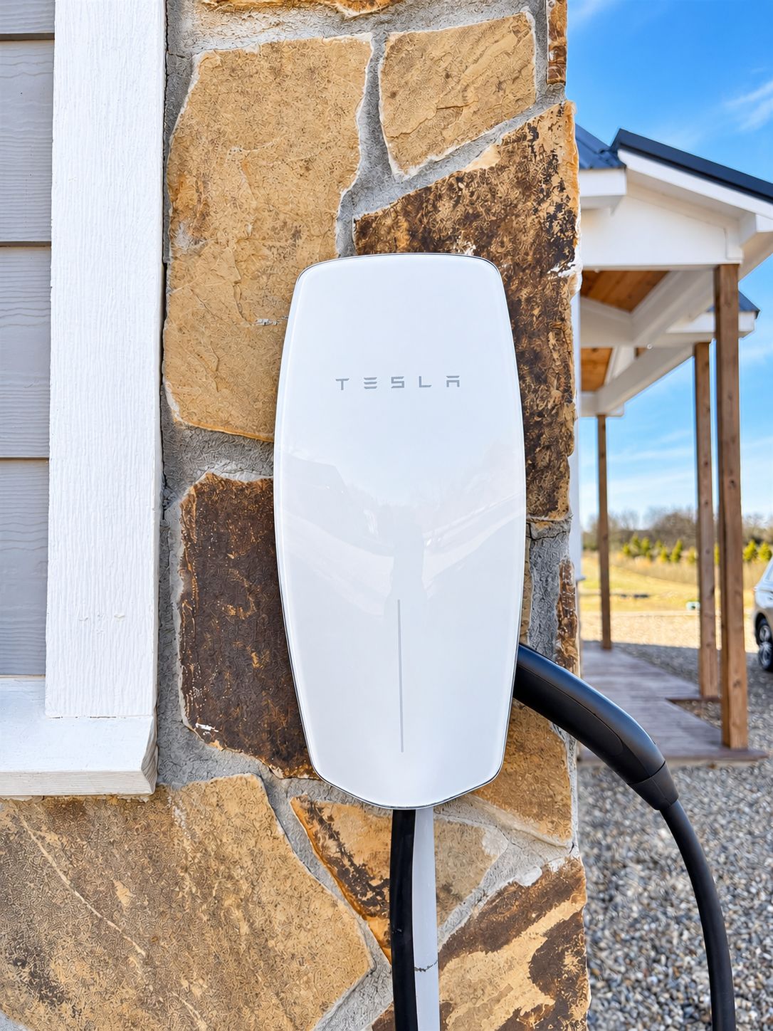 Une borne de recharge pour véhicules électriques Tesla fixée à un mur en pierre.