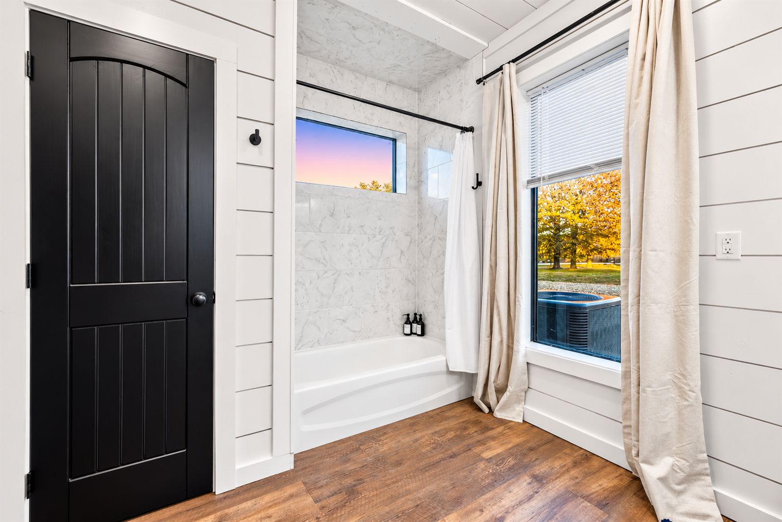 King Suite 1 - Ensuite Bathroom | Bright bathroom featuring a bathtub and shower, tall window, and white shiplap walls. Refresh after an afternoon at the pool or exploring nearby trails.