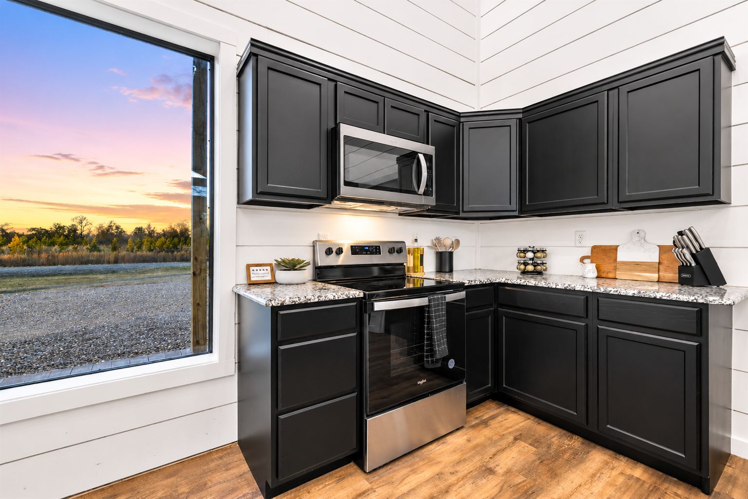 Modern kitchen with dark cabinets, stainless steel stove and microwave, and countertop cooking tools—ready for easy breakfasts or homemade group dinners.