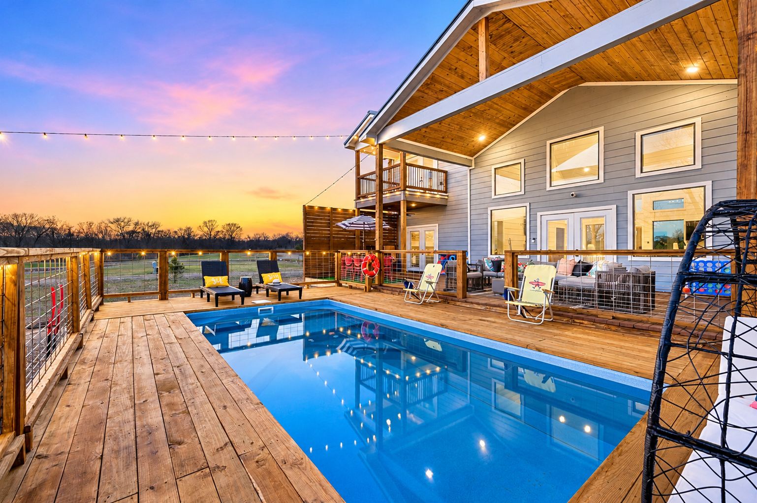 A wooden deck with a pool, outdoor seating, and a covered area with a view of the landscape.