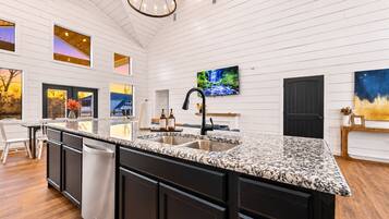 Spacious kitchen island with granite counters, sink, and stainless dishwasher opens to the living and dining areas—ideal for cooking while everyone gathers.