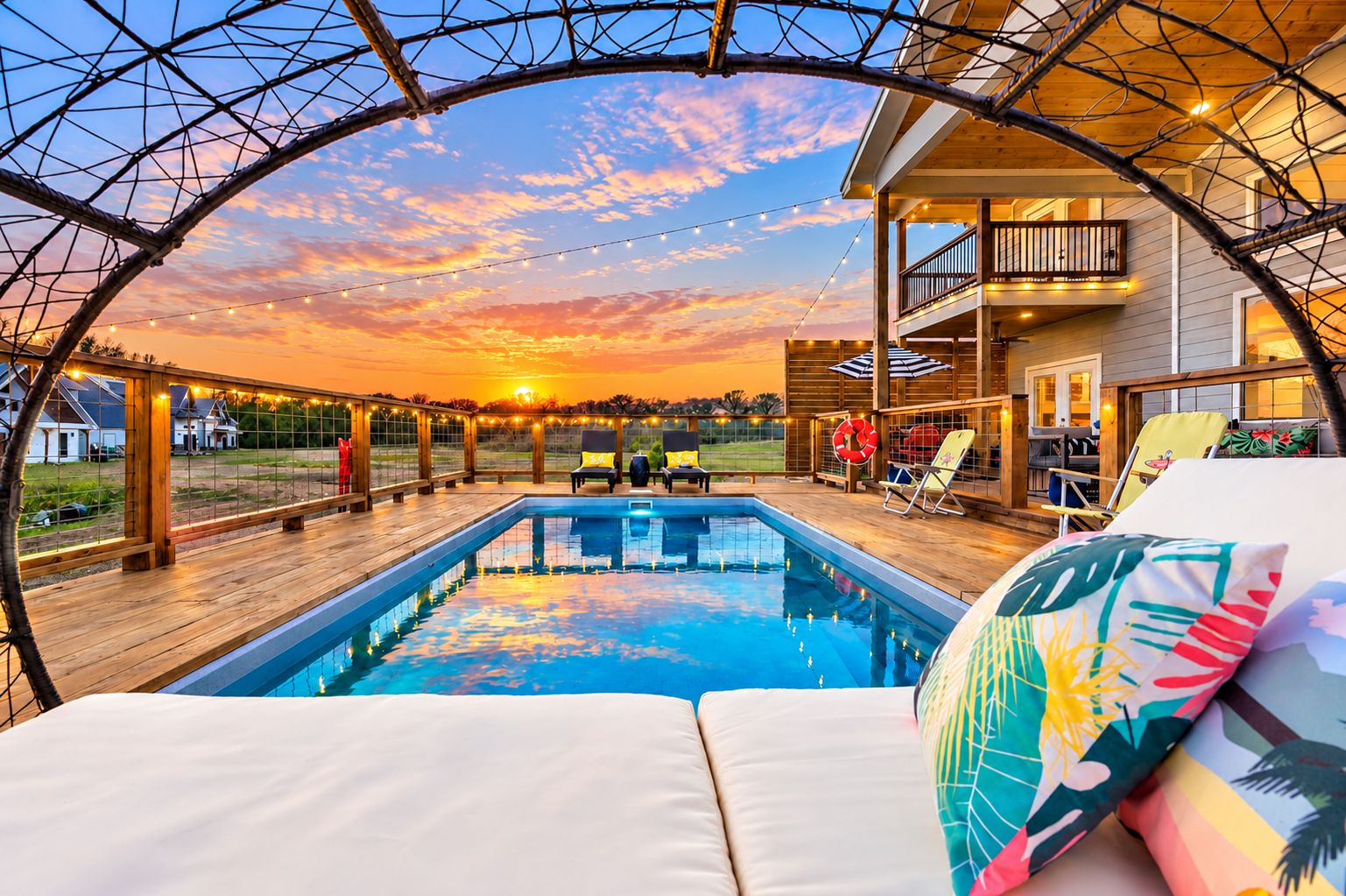 A pool area with a sunset view, lounge chairs, and a covered deck.