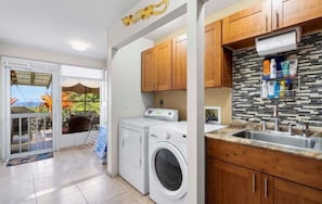 Un espace buanderie comprenant un lave-linge, un étendoir et des armoires en bois.
