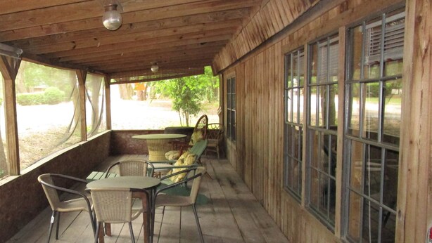 A wooden deck with a table and chairs, large windows, and a ceiling light. - The Chalet On the Suwannee River (Mayo)