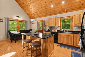 Una cocina con armarios de madera, encimera negra y barra con taburetes.