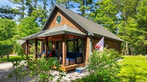 Eine Lodge mit überdachter Veranda, einer Flagge und einer natürlichen Umgebung.