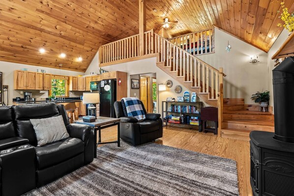 A spacious living area with a fireplace, a dining table, and a kitchen in the background.