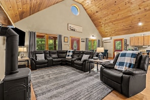 A cozy living room with a sectional sofa, a fireplace, and a kitchen in the background.