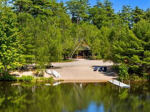 A lakeside cabin with a dock, surrounded by dense trees.